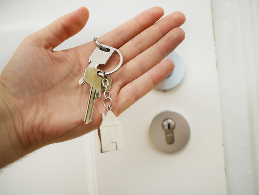 House keys held in a hand at the doorway of a home.
