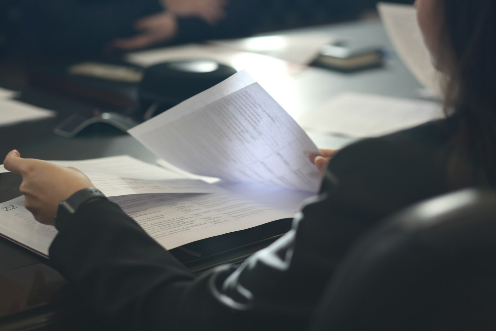 Woman reading a sheet of paper while seated at a table.